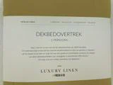 En etiket til et luksusdynebetræk i hør til én person på hollandsk med oplysninger om størrelse, materiale og funktioner, og mærket Fresh & Co står nederst.