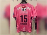 Lyserød sportstrøje med nummeret 15 og navnet KLOKKER på ryggen samt forskellige logoer fra virksomhedssponsorer.