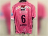 En lyserød fodboldtrøje med nummer 6 og navnet BRANDI på ryggen, med flere sponsorlogoer.