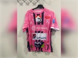 En lyserød og lilla sportstrøje med forskellige firmalogoer, et lyserødt opmærksomhedsbånd og tallet 7 på forsiden.