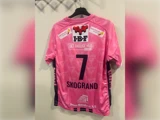Lyserød fodboldtrøje med nummer 7 og navnet SKOGRAND på ryggen samt forskellige sponsorlogoer.