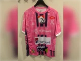 Håndboldtrøje med mønster i lyserødt og lilla, med sponsorlogoer og nummer 11 på forsiden.