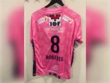 Lyserød trøje med nummer 8 og navnet ROBERTS på ryggen, med forskellige sponsorlogoer.