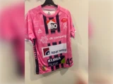 Lyserød og sort mønstret sportstrøje med flere sponsorlogoer og tallet 42 på forsiden.