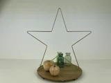 En stjernedekoration i ståltråd står på en træbase med to æbleornamenter i træ og to små vintageglasflasker foran.