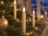 Tre flammeløse LED-stearinlys, der er fastgjort til grenene på et pyntet juletræ.