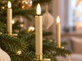 Tre elektriske, tilspidsede stearinlys, der lyser på et juletræ.