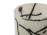 Nærbillede af en cylindrisk vase med hvid mosaikoverflade og abstrakte sorte streger og stænk som dekoration.
