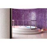 En rund, hvid jacuzzi med metalgelænder står på en trappe omgivet af lilla mosaikfliser, og der står stearinlys på gulvet i nærheden.