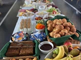 Et bord fyldt med forskelligt brød, frugt, granola, smørepålæg, salater, grøntsager og forskellige morgenmadsprodukter, opstillet som en buffet til et måltid.