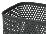Nærbillede af en sort, rektangulær, perforeret metalkurv med afrundede hjørner og et mønster af jævnt fordelte cirkulære huller.