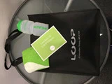 En sort LOOP Fitness-taske på et metalbord, der indeholder en grøn og hvid vandflaske, et grønt og hvidt håndklæde og et grønt gavekort med påskriften "Gavekort til LOOP Fitness".
