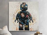 Et farverigt graffiti-maleri af en LEGO minifigur med ord som BRICK og forskellige tags, der hænger på en væg over en sofa og et lille bord med bøger.