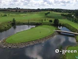 Luftfoto af en golfbane med en ø-green omgivet af vand, forbundet til land med en lille træbro; "ø-green"-tekst nederst til højre.