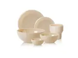 Et sæt med seks cremefarvede keramikfade, herunder tre skåle, to tallerkener og et krus, arrangeret på en hvid baggrund.