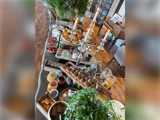 Et langt træbord dækket med en række forskellige forretter, herunder skåle med tomater, kiks, marmelade, wienerbrød og en sølvkandelaber som bordpynt.