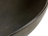 Nærbillede af kanten og overfladen på en mørk, rund keramikskål, der viser dens strukturerede finish og bløde kurve.