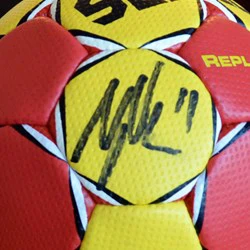 Et nærbillede af en gul og rød fodbold med en sort autograf og tallet 11 skrevet på et af de gule felter.