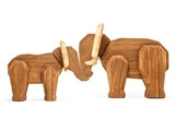 To elefantfigurer af træ, en større og en mindre, står side om side med front mod hinanden. Begge har lyse stødtænder og er udformet med enkle geometriske former.