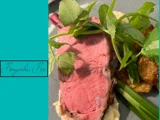 En tallerken med en tyk skive roastbeef, pyntet med frisk grønt og serveret sammen med sprøde, ristede kartofler.