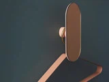 En moderne, oval vægkrog med metallisk overflade holder en minimalistisk, kantet håndklædeholder fast på en mørkeblå væg.