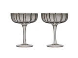 To klare coupéglas med stilk og lodrette striber, der står side om side på en hvid baggrund.