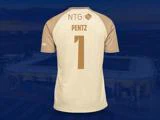 En beige og brun fodboldtrøje med navnet PENTZ og tallet 1 på ryggen, vist mod en sløret stadionbaggrund.
