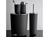 Et sæt sort, mat badeværelsestilbehør med skraldespand, tandbørsteholder, sæbedispenser og toiletbørste på en sort overflade.