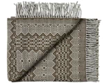 Et foldet vævet tæppe med frynsekanter og et geometrisk mønster i brun og beige. Det ene hjørne er vendt om, så man kan se bagsiden.