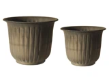 To brune, runde, riflede blomsterpotter i forskellige størrelser placeret side om side på en almindelig hvid baggrund.
