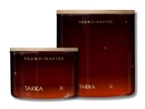 To ravfarvede glaskrukker med trælåg, mærket "SKANDINAVISK TAKKA", med minimale guldaccenter og et gradientdesign.