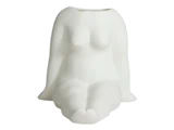 En hvid keramikvase formet som en siddende, stiliseret menneskefigur med forenklede træk og uden hoved.