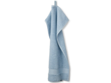 Et lyseblåt håndklæde med struktur hænger i en løkke mod en hvid baggrund.