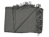 Et sort og hvidt houndstooth-mønstret tørklæde med frynsede kanter, lagt fladt med det ene hjørne foldet om.