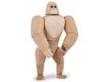 En gorillafigur af træ med bevægelige led står oprejst mod en almindelig hvid baggrund.