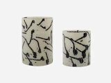To cylindriske vaser med hvid bund og abstrakte sorte mønstre, placeret side om side på en ensfarvet baggrund.