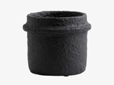 En rund, sort, struktureret urtepotte med en ru, ujævn overflade og en let udvidet kant mod en almindelig hvid baggrund.