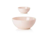 To lyserøde keramikskåle i forskellige størrelser på en hvid baggrund, med den store skål i forgrunden og den lille skål i baggrunden.