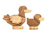 To legetøjsænder af træ, en større og en mindre, lavet af forskellige nuancer af træ, er placeret side om side på en hvid baggrund.