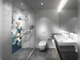 Moderne badeværelse med brusekabine med sekskantede fliser i blå, grå, brun og hvid, væghængt toilet, rektangulær vask og stort spejl over en sort bordplade.