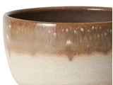 Nærbillede af en keramikskål med brun og beige glasur, blank overflade og afrundet kant.