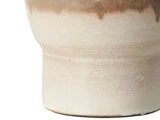 Nærbillede af den nederste del af en keramikvase med en mat beige bund og en blank brun drypglasur nær toppen.