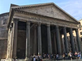 Pantheon i Rom med høje søjler og en trekantet fronton er fyldt med turister ved indgangen på en solrig dag.