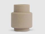Beige, cylindrisk keramikvase med en mat finish, der har en bred midtersektion og en smallere top og bund, sat mod en almindelig lysegrå baggrund.