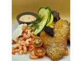 En tallerken med panerede fiskefileter, rejer, agurker, citronskiver, cherrytomater, grønt, en klat sort kaviar og en skål med cremet dippesauce.