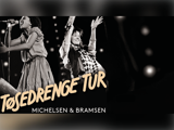 To personer optræder energisk på scenen med mikrofoner. Den overliggende tekst lyder "TøsEDRENGE TUR MICHELSEN & BRAMSEN" med fede, stiliserede bogstaver.