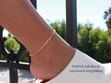 Et nærbillede af en fod med en dobbelt ankelkæde i guld og en hvid sko, med grønne planter og et sort rækværk i den slørede baggrund. Dansk tekst i nederste højre hjørne.