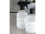 To klare flasker mærket ALTUM, en med spraydyse og en med skruelåg, står på en grå flade. Sprayflasken er mærket glasrens.