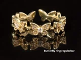 En guldring med sommerfuglemønstre med indlejrede ædelstene, vist på en reflekterende sort overflade. Teksten lyder Butterfly ring regulerbar.
