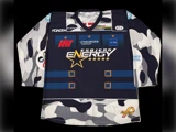 En langærmet hockeytrøje med et blåt, hvidt og gråt camouflagemønster, guldstjerner, sponsorlogoer og teksten »Esbjerg Energy« på brystet.